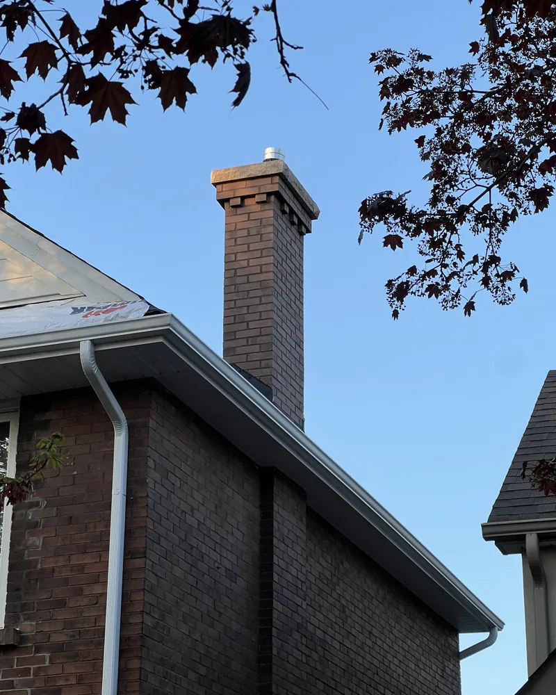Rebuilt brown brick chimney with corbelled detailing and a new cast stone crown, matched masonry, Toronto