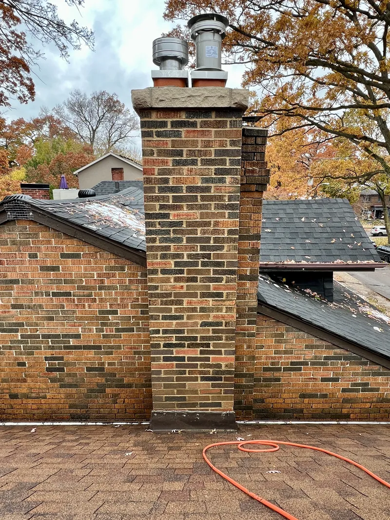 Rebuilt multi-tone brick chimney with new stainless flue caps and stone crown, drone view, Toronto