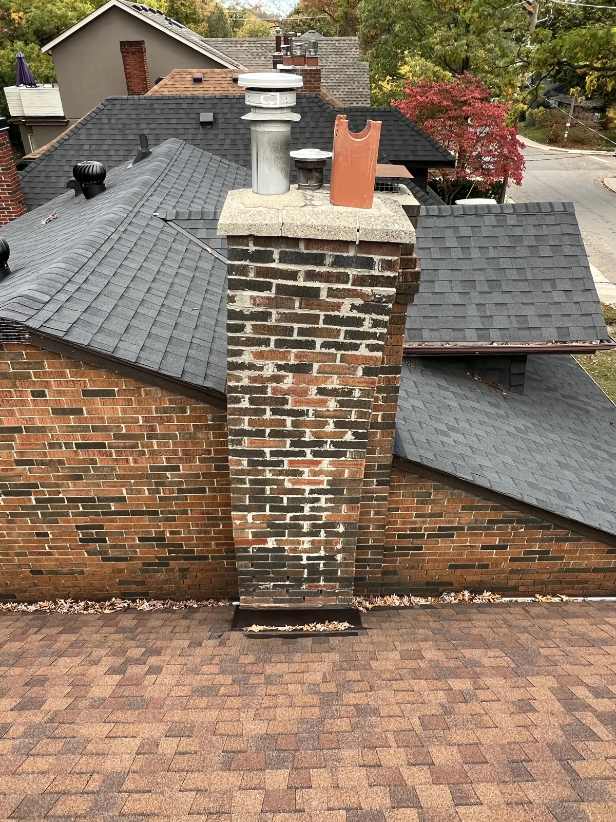 Weathered dark brick chimney with washed-out mortar joints before rebuild, drone view, Toronto