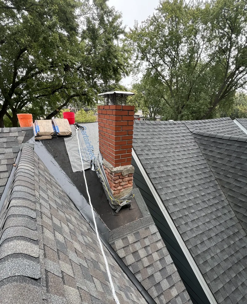 Failed red brick chimney tarped mid-rebuild with base courses removed, Toronto roof