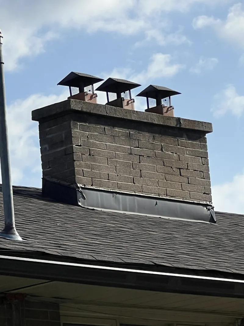 Spalling grey-brown three-flue chimney with cracked mortar before rebuild, Toronto
